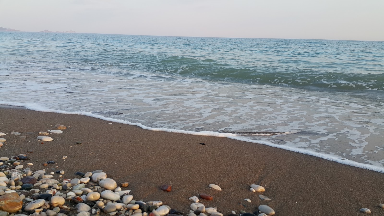 Fotografija Finike Halk Plaji II z musta hiekka ja kivi površino