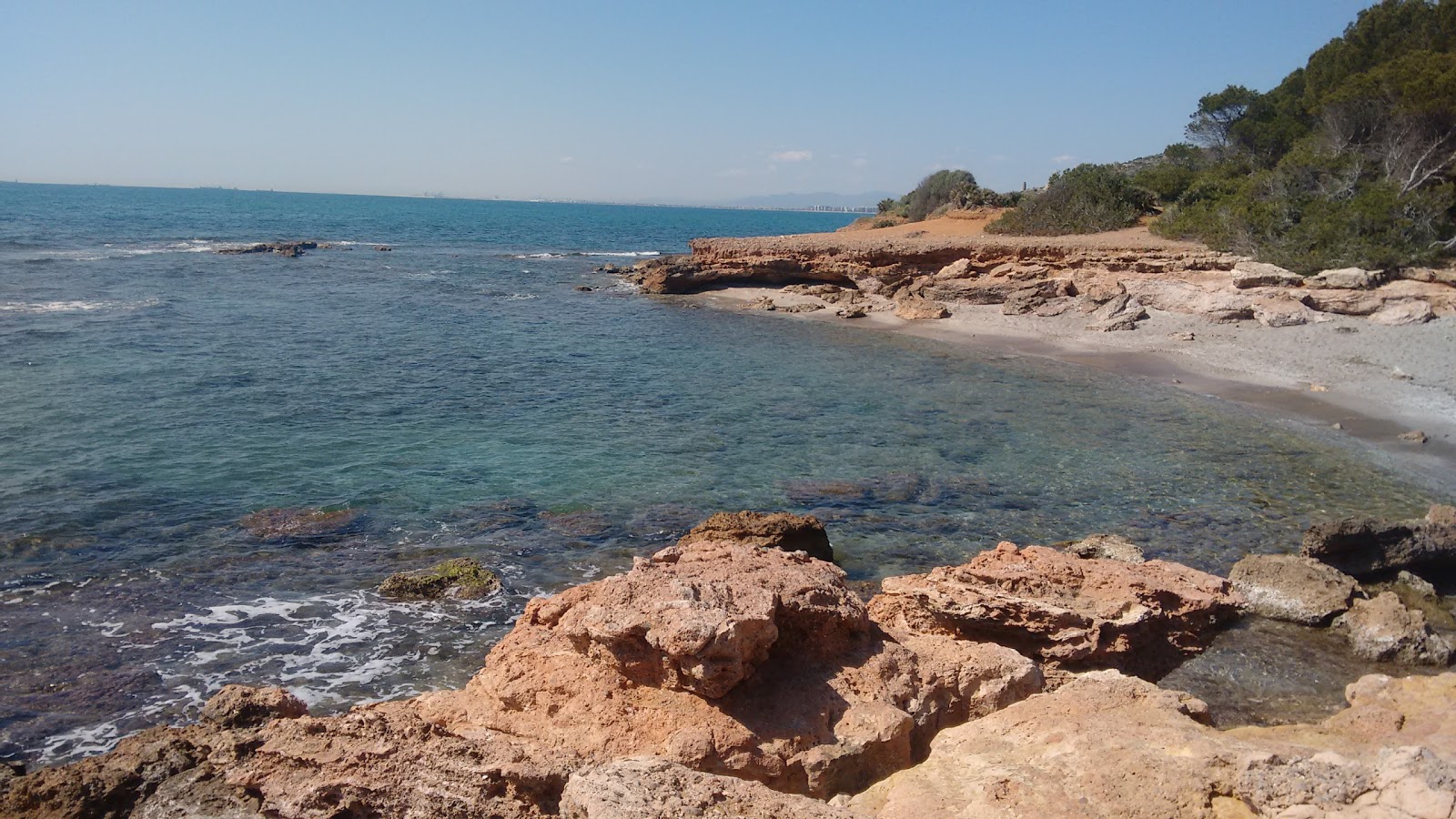 Foto di Playa en Via Verda con una superficie del sabbia grigia e rocce