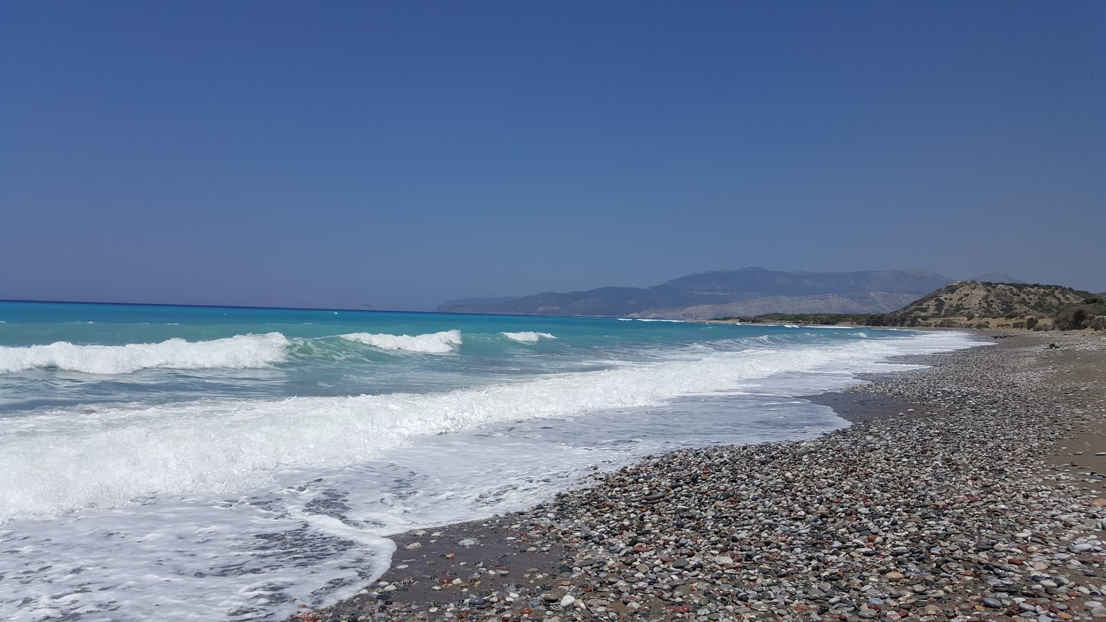 Foto di Kouloura Beach con una superficie del sabbia nera e ciottoli