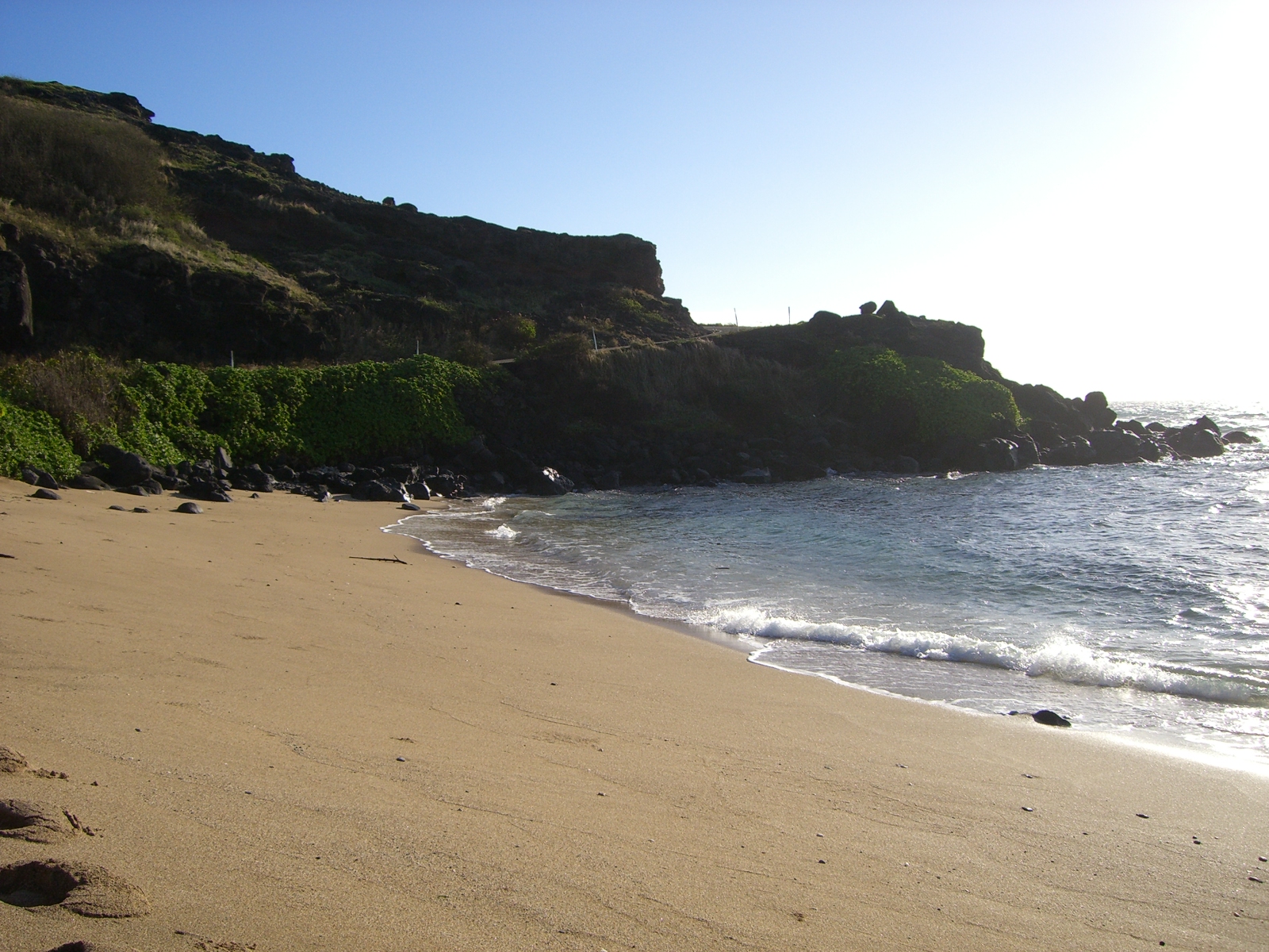 Valokuva Kamehameha Beachista. pinnalla kirkas hiekka ja kivet:n kanssa