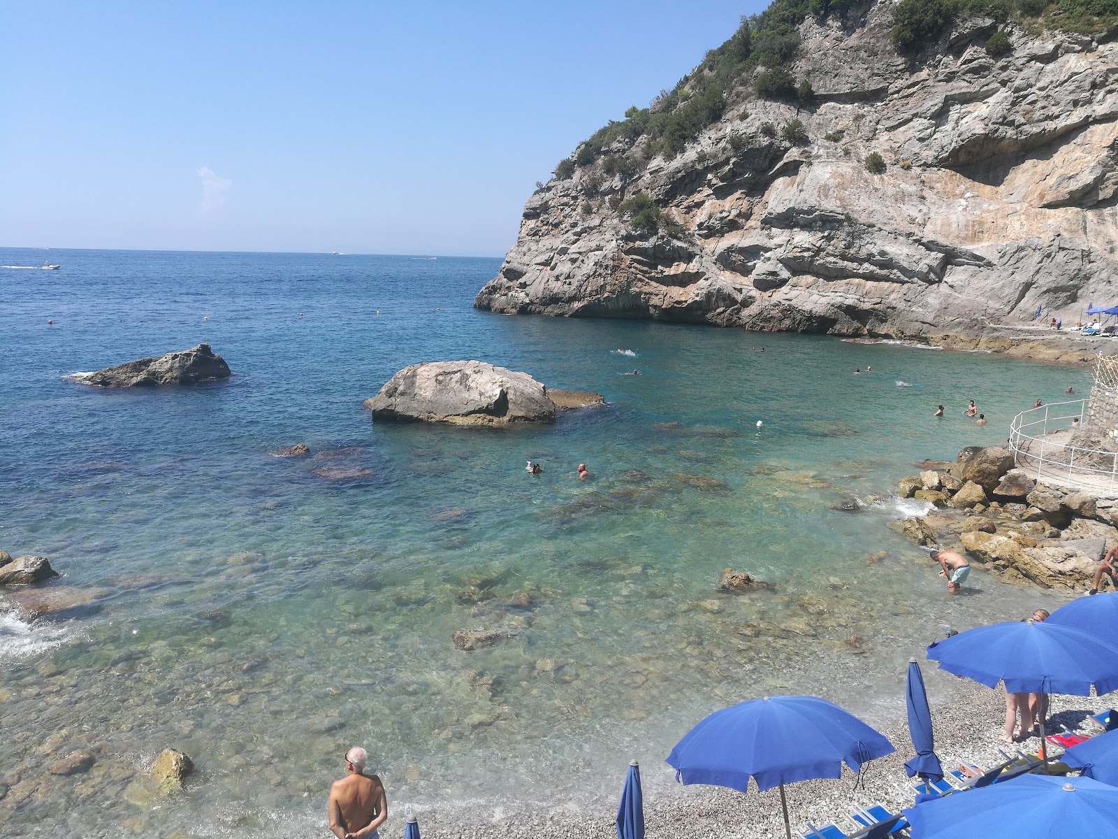 Foto af Baia delle Sirene bakket op af klipperne