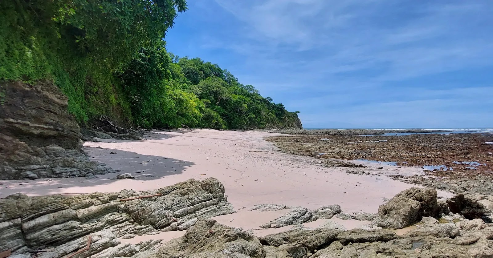 Foto de Playa Rosada com areia bege e rochas superfície