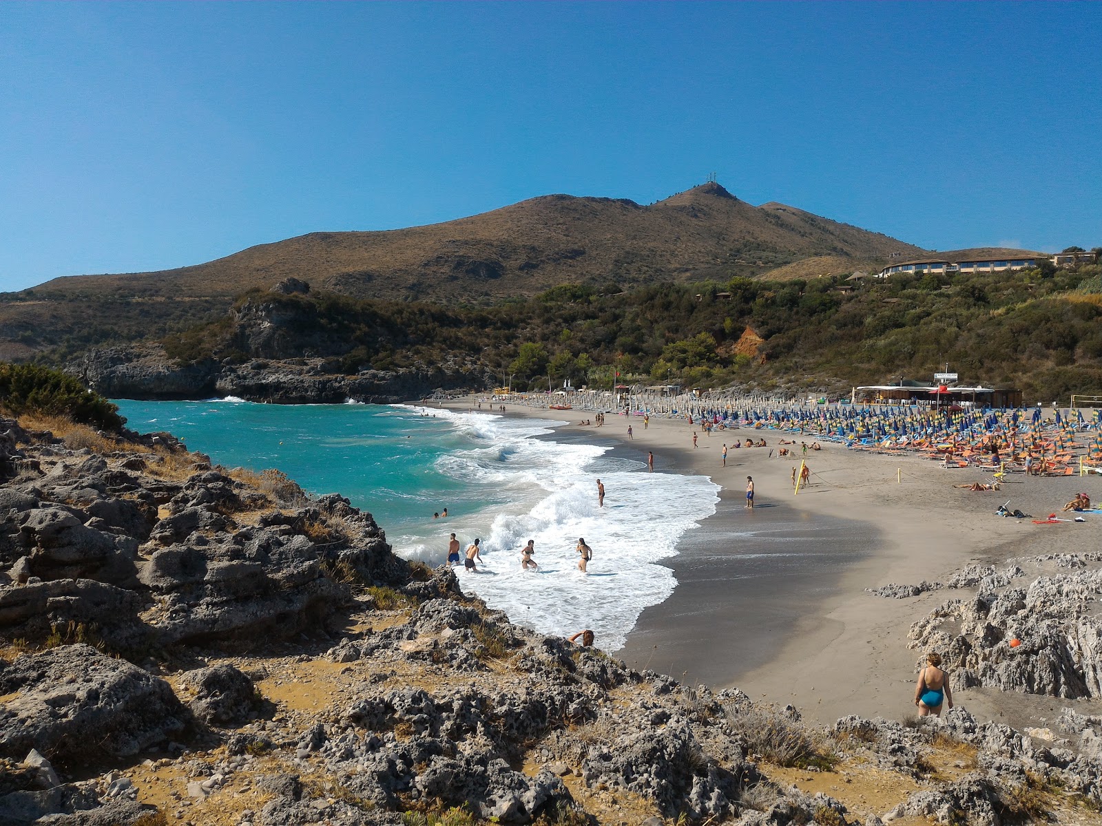 Foto af Spiaggia di Capogrosso bakket op af klipperne