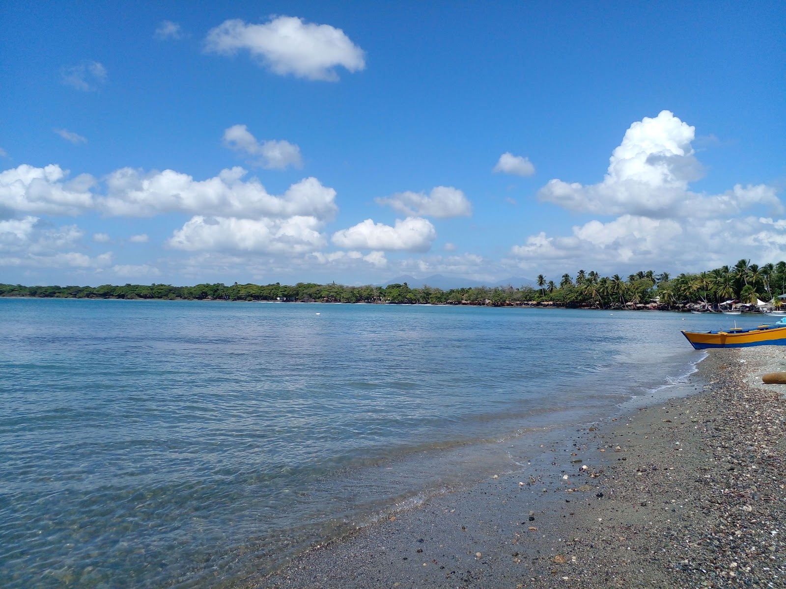 Valokuva Cocoland beachista. pinnalla harmaa hiekka:n kanssa