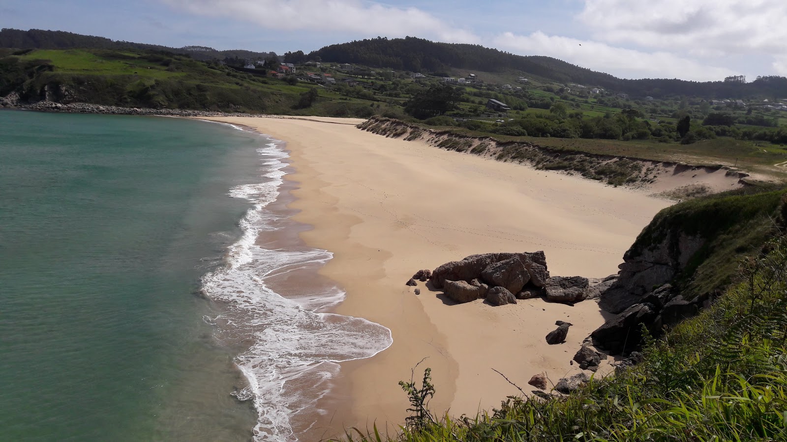 Valokuva Playa de Esteiroista. tukeutunut kallioilla