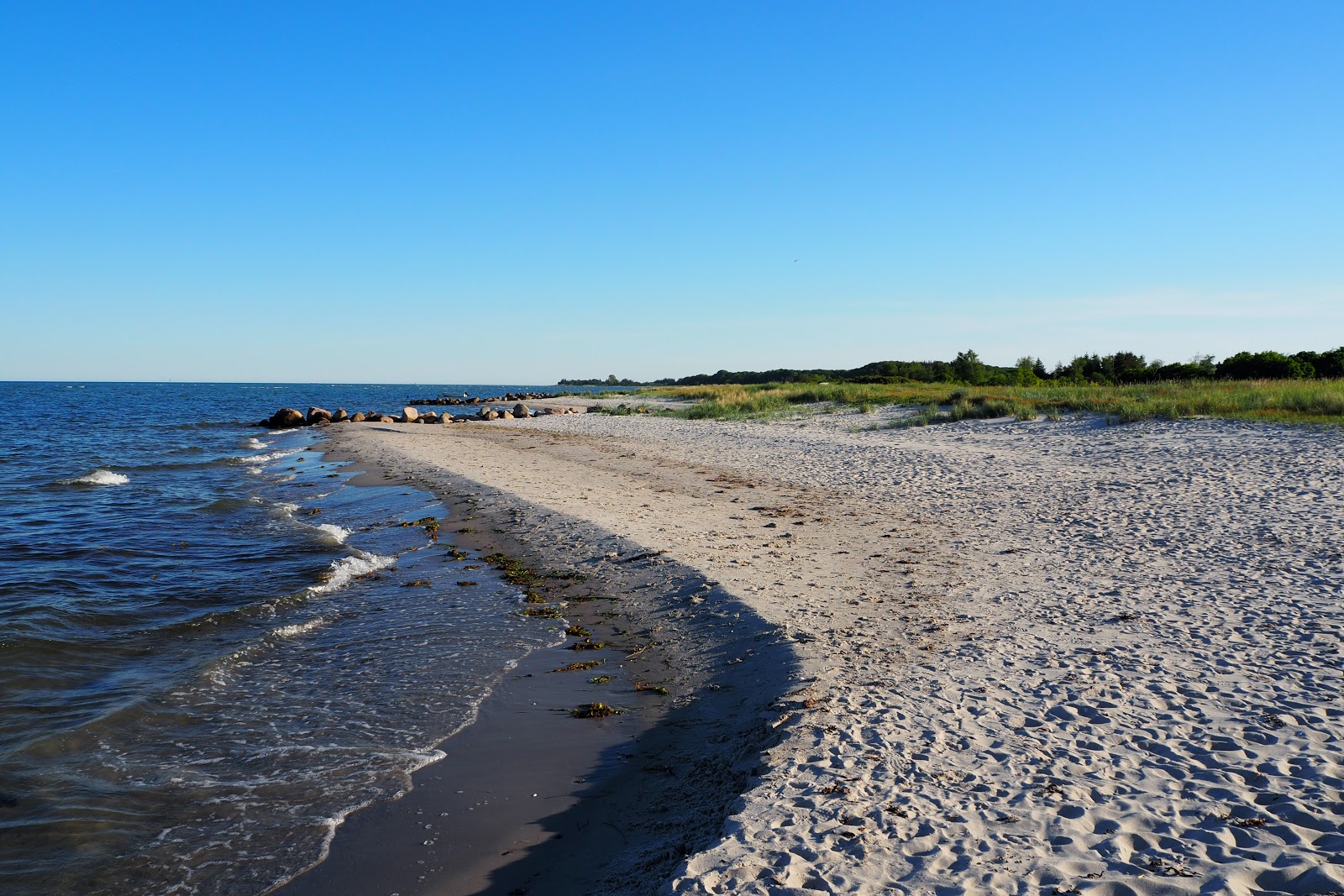 Drejet Beach的照片 带有明亮的沙子和岩石表面