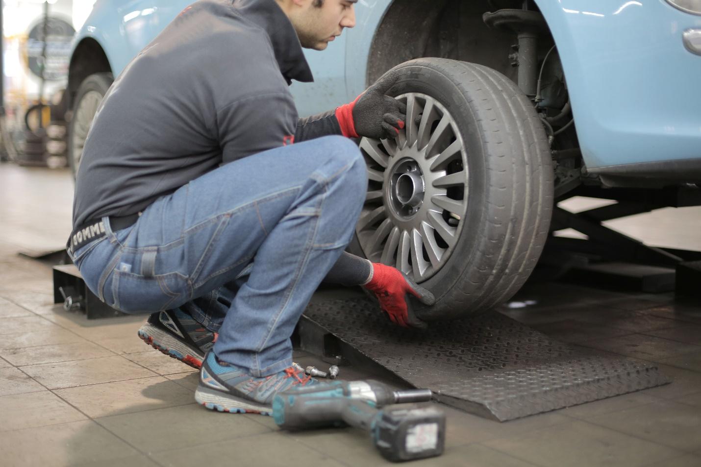 A person working on a car tire  Description automatically generated with low confidence