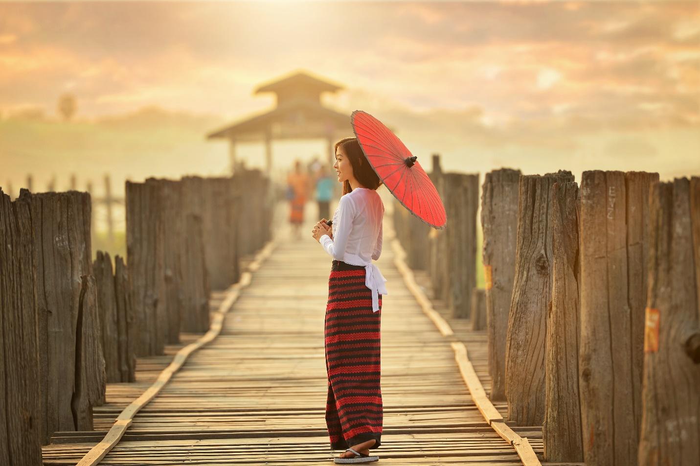 A person holding an umbrella on a boardwalk  Description automatically generated with medium confidence