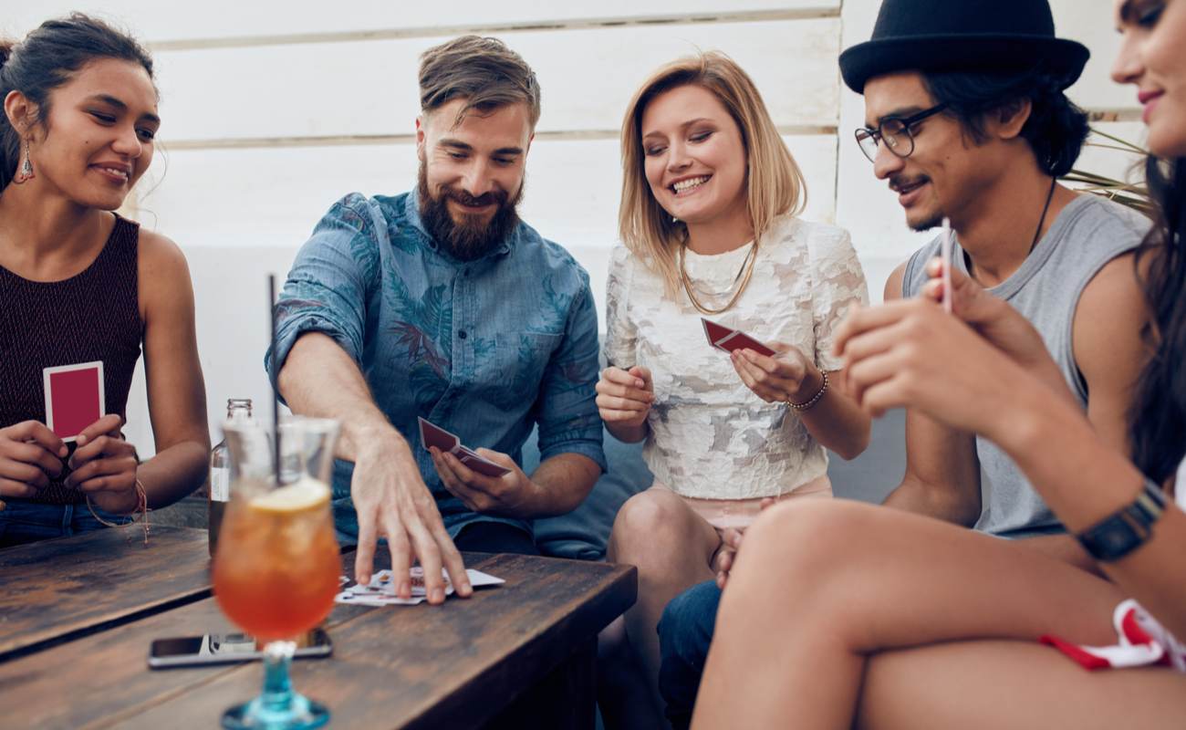 Group of friends sat around a table playing a card game