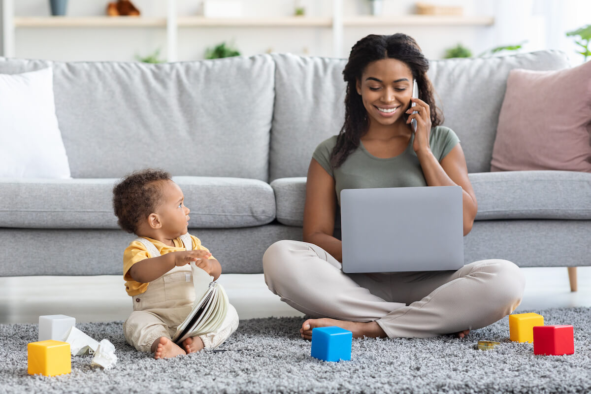 Woman working on the floor while her baby plays beside her