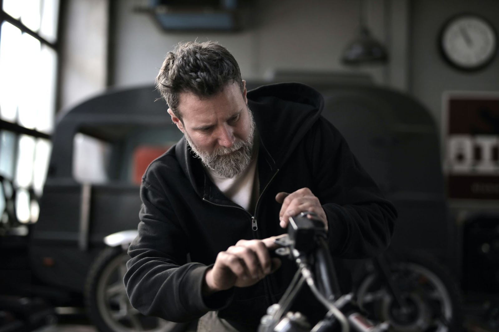 A man in a repair shop using a diagnostic code scanner on vehicle part