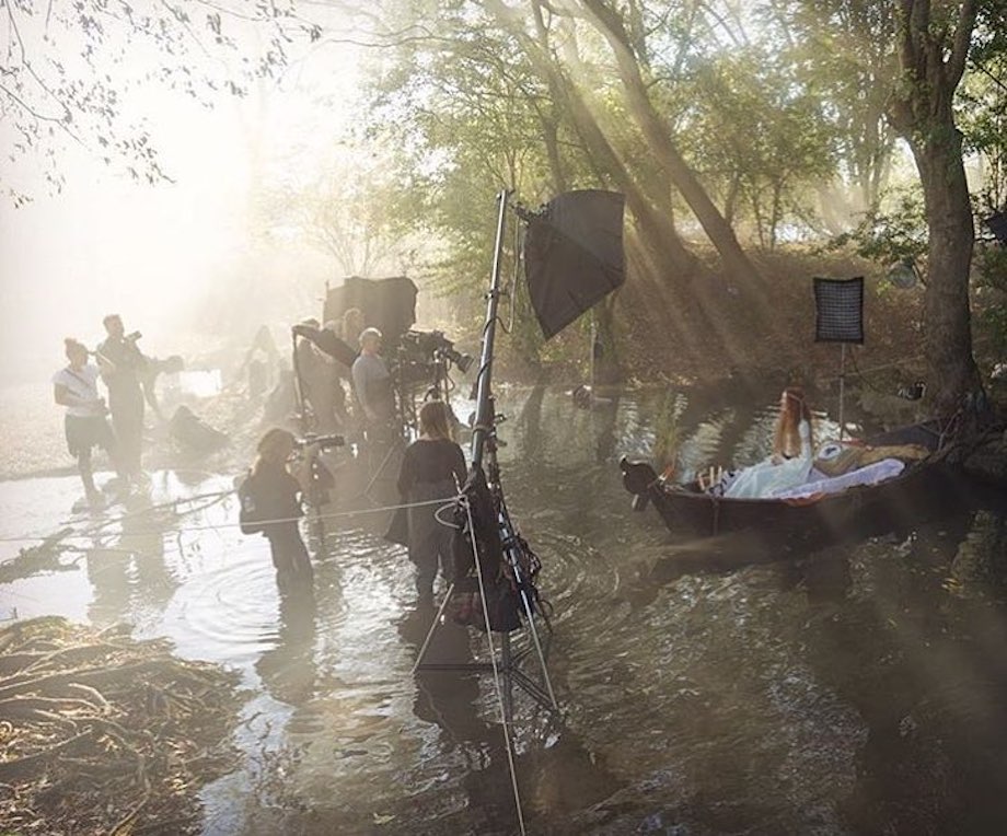 Image of a photoshoot where you see the wardrobe stylist and other crew members wading through knee deep water.