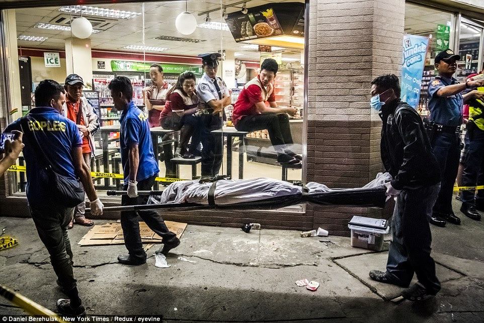 Funeral parlor workers carry away Edwin Mendoza Alon-Alon, 36, who was shot in the head outside a 7-Eleven store, in the Paranaque area of Manila, Philippines