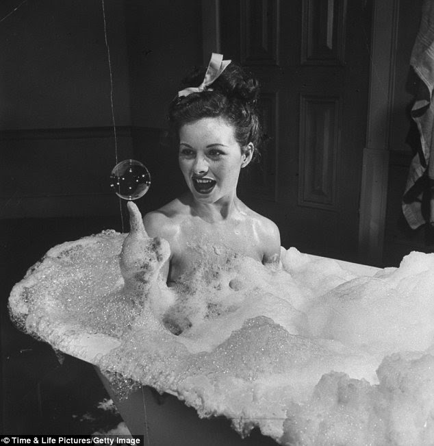 Soap suds: Actress Jeanne Crain balancing a huge soap bubble on her index finger as she luxuriates in a bubble bath in scene from the movie Margie