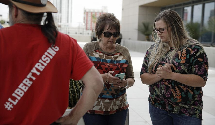 Carol Bundy, center, wife of Nevada rancher Cliven Bundy, looks at her phone beside Bailey Logue, daughter of Cliven Bundy, while waiting for a verdict outside of the federal courthouse, Monday, April 24, 2017, in Las Vegas. A jury found two men guilty of federal charges Monday in an armed standoff that stopped federal agents from rounding up cattle near Cliven Bundy's Nevada ranch in 2014. Jurors said they were deadlocked on charges against four other men, and the judge told them to keep deliberating. (AP Photo/John Locher)