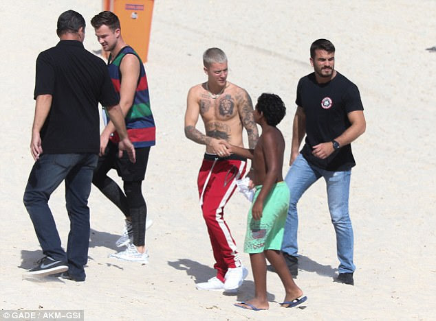 Cordial: Em um ponto ele foi capturado apertando as mãos com um jovem fã em botas de banho verde que correu até ele na praia
