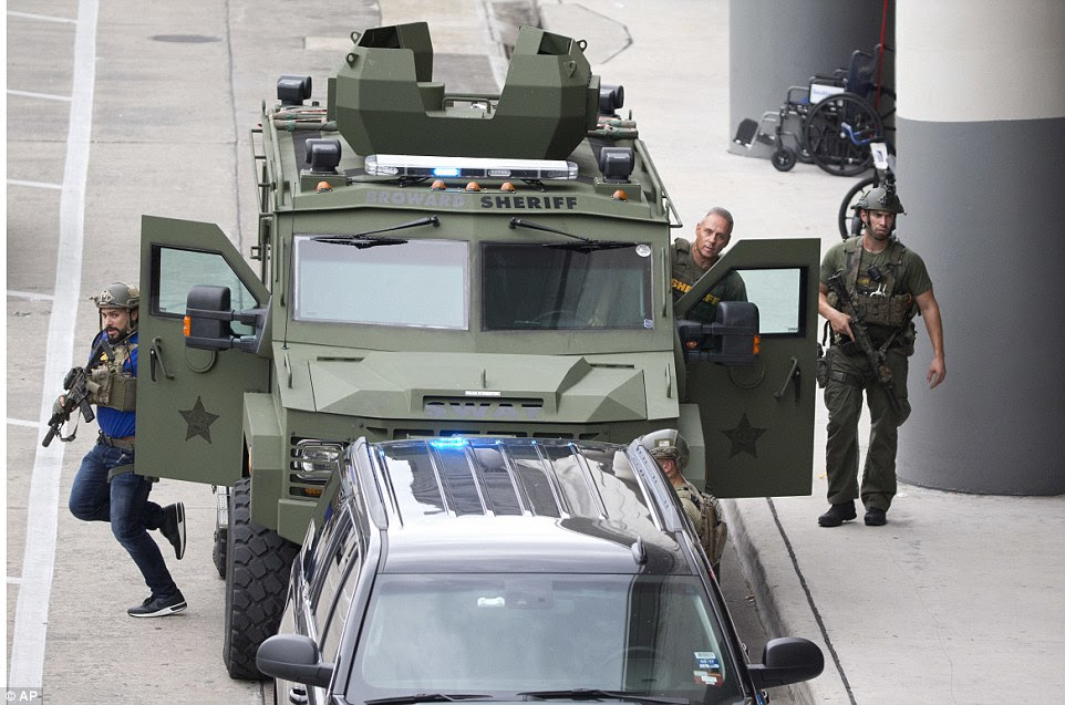 Law enforcement personnel arrive in an armored car at the airport after the deadly shooting that saw five killed