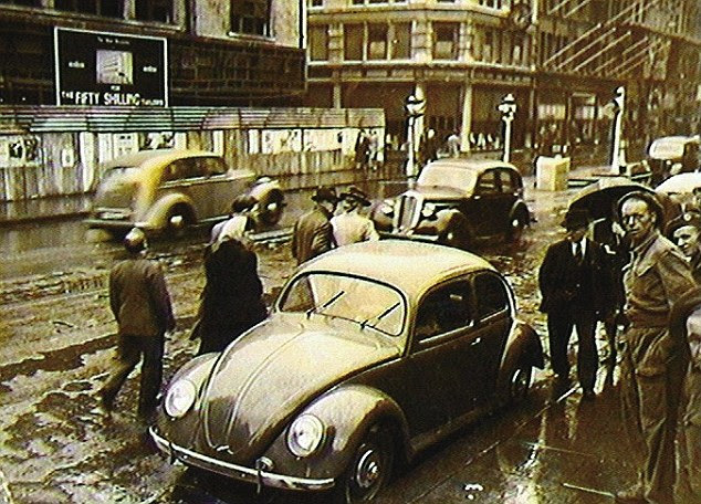 Rare sight: A VW Beetle attracts admiring glances as it is in the rain parked in Oxford Street in London in June 1946