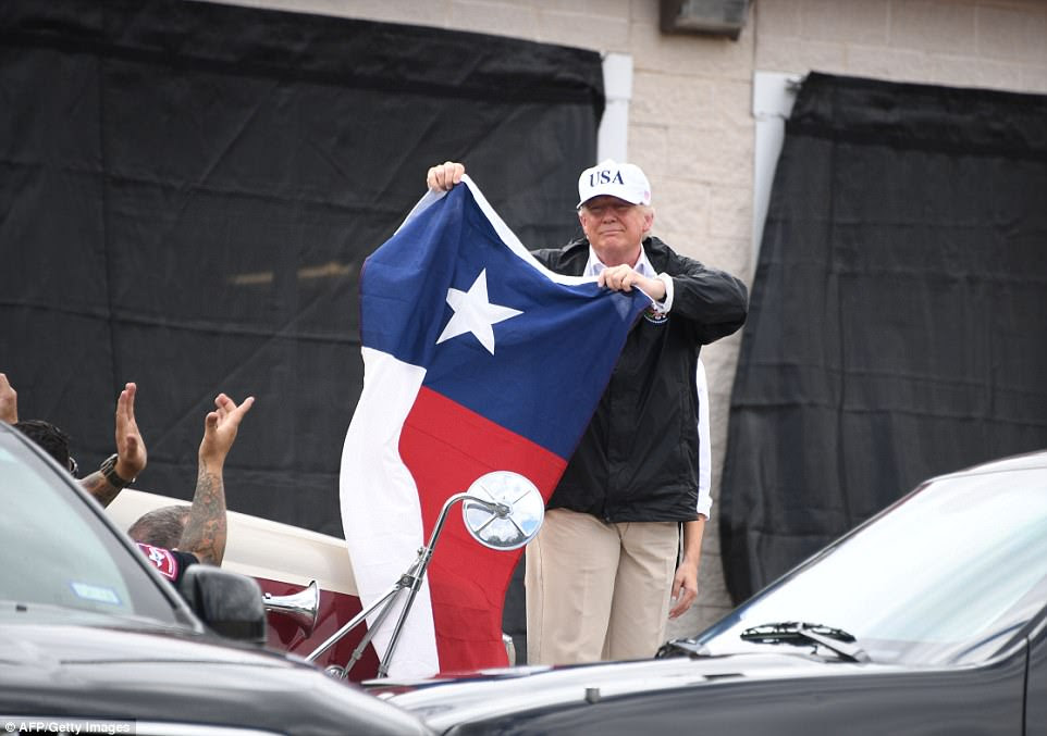 President Trump waves a Texas flag as he visits communities in Corpus Christi on Tuesday 