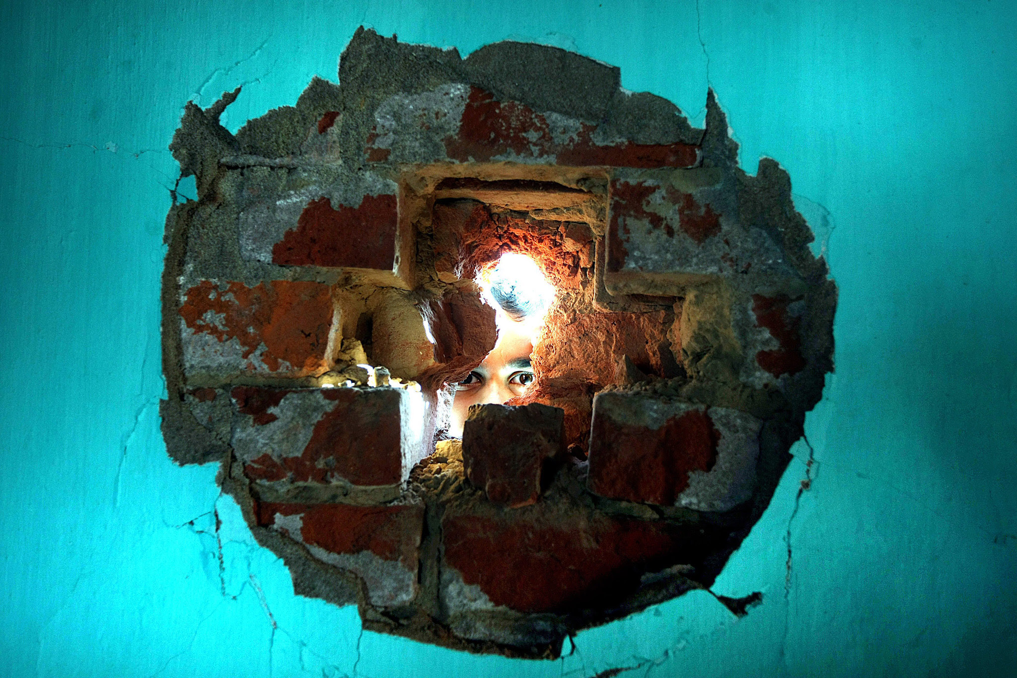 Indian villager looks from hole in the wall of a building allegedly damaged by shelling from the Pakistani side of the disputed Kashmir border, at Arnia village, about 45 KM from Jammu, the winter capital of Kashmir, India, 30 January 2015. According to local sources in a major ceasefire violation by Pakistani Rangers three civilians were wounded on the Indian side of the disputed India-Pakistan Kashmir border when Pakistani troops allegedly fired mortar shells at border posts and villages.