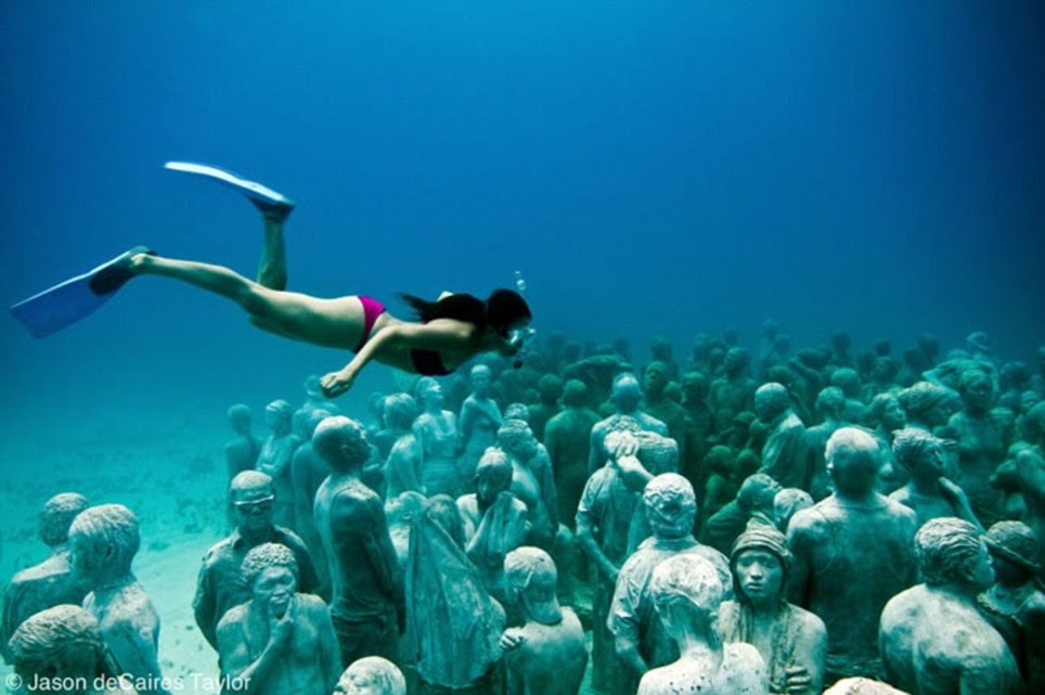 Undersea community: A woman dives metres below the surface off Cancun, Mexico to explore hundreds of men, women and children molded from the above on land