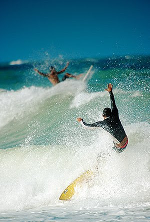 Two people surfing on a beach in Brazil.