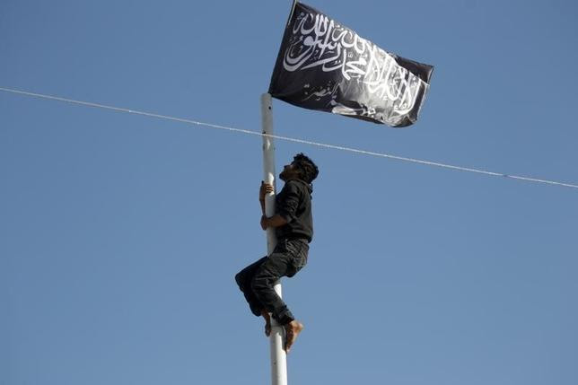 A member of al Qaeda's Nusra Front climbs a pole where a Nusra flag was raised at a central square in the northwestern city of Ariha, after a coalition of insurgent groups seized the area in Idlib province May 29, 2015. REUTERS/Khalil Ashawi