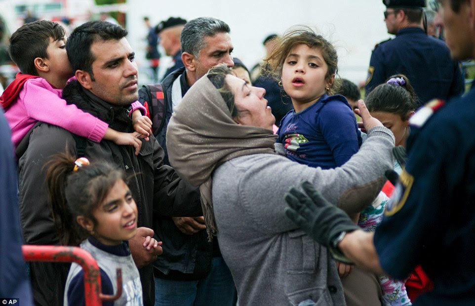 Migrants carry children as they wait to be taken through the border between Austria and Hungary this morning