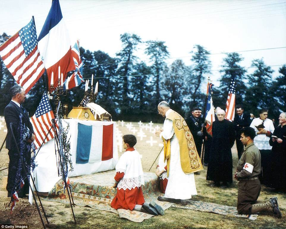 A catholic priest is performing a religious service in the Normandy American Cemetary of Colleville sur Mer in July 1944. The town is near Omaha Beach where the largest battle of the invasion took place after the landings on June 6