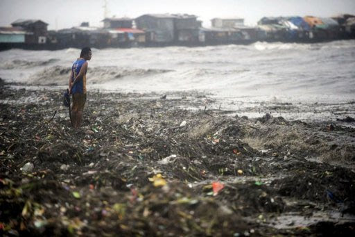 A man looks for usable materials amongst garbage washed up by strong waves caused by super-typhoon Nanmadol