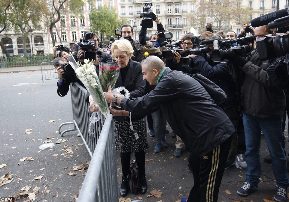 People tie flowers to railings outside the Bataclan concert venue, which was stormed by gunmen last night
