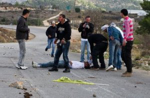 Nabi Saleh- A group of Palestinian men surround Mustafa Tamimi after he was shot