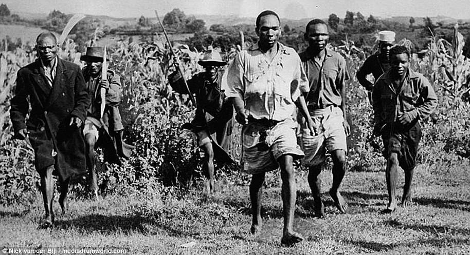 Home Guard and a police officer escort four captured Mau Mau. The Mau Mau had suffered badly from the introduction of British colonialism in the late 19th Century and had lost grazing grounds and homesteads to white farmers, many from the British upper classes