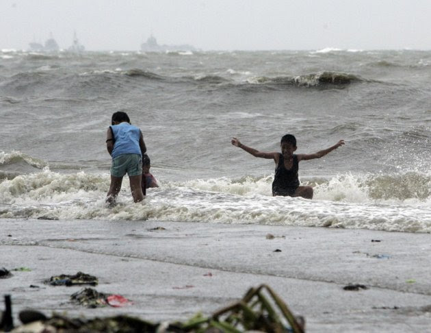 A boy enjoys the surf as another one looks for salvagable materials wash ashore due to Typhoon Nanmadol Saturday, Aug. 27, 2011 in Manila, Philippines. Forecasters said the typhoon hit the northeaster