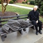 The Rev. David Buck sits next to the Jesus the Homeless statue that was installed in front of his church, St. Alban's Episcopal, in Davidson, N.C.