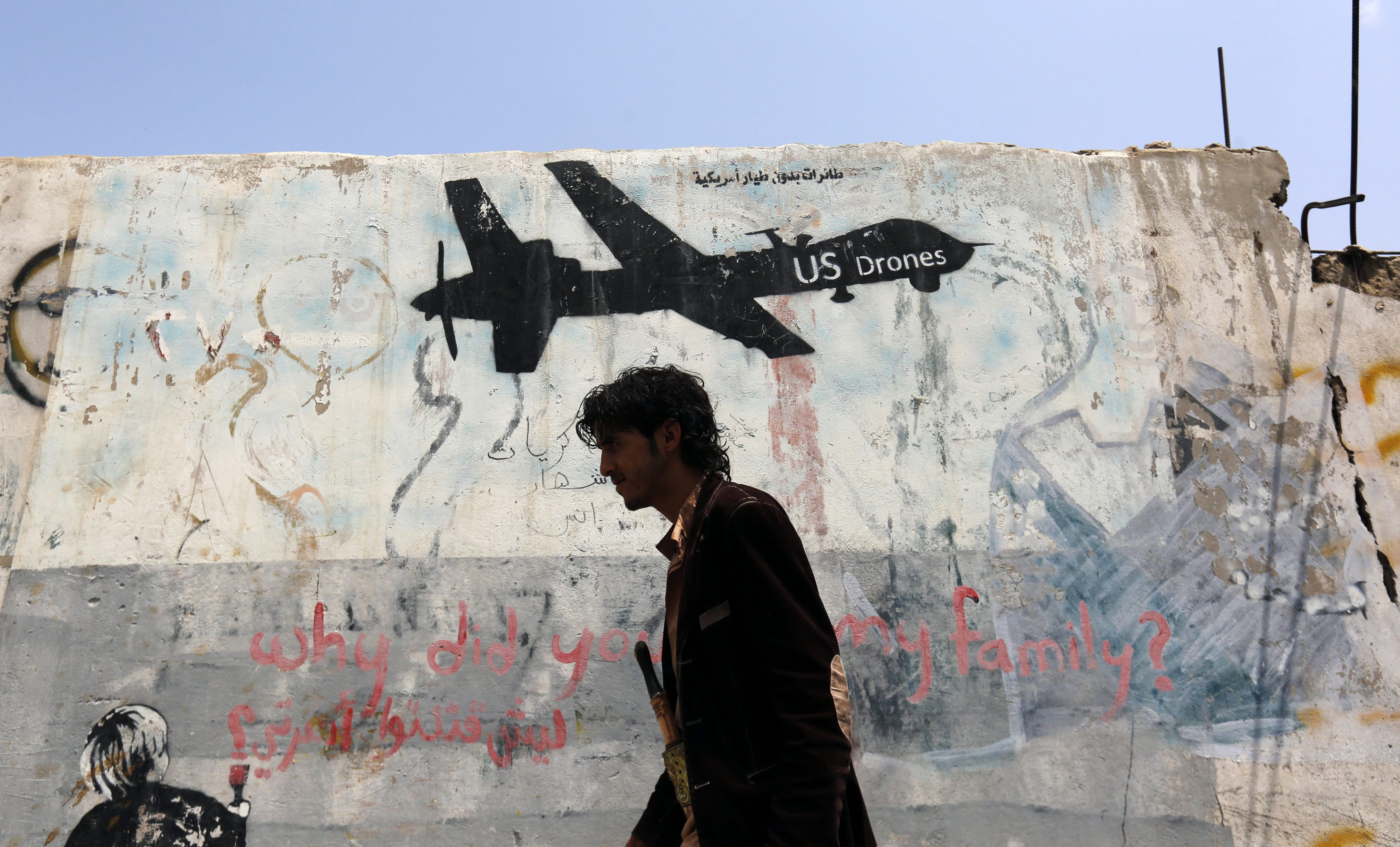 A Yemeni walks past graffiti protesting US drone operations in Yemen, few hours after a US drone attack on suspected al-Qaeda militants