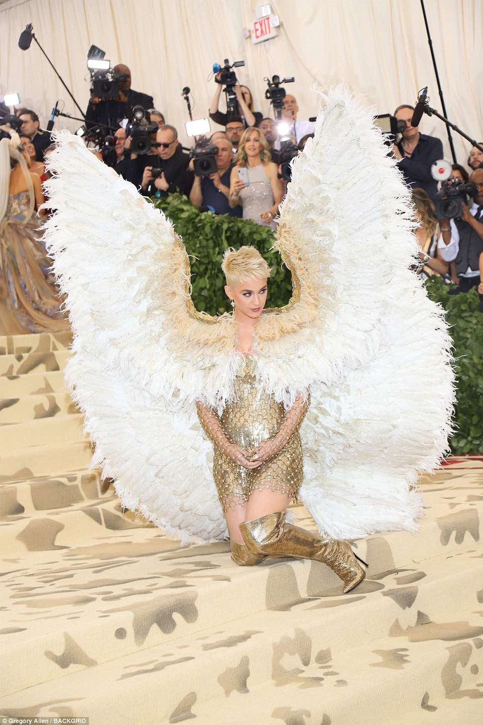 Pare e posar: Katy Perry escolheu um vestido Versace dourado e botas combinando, adicionando enormes asas de anjo