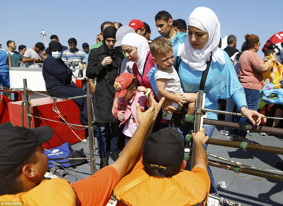 A new start: Members of the Turkish coast guard help a Syrian migrant family to disembark on the shore in Cesme, Turkey