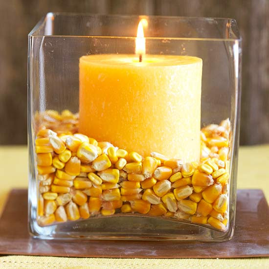 Yellow candle surrounded by corn in a square class holder