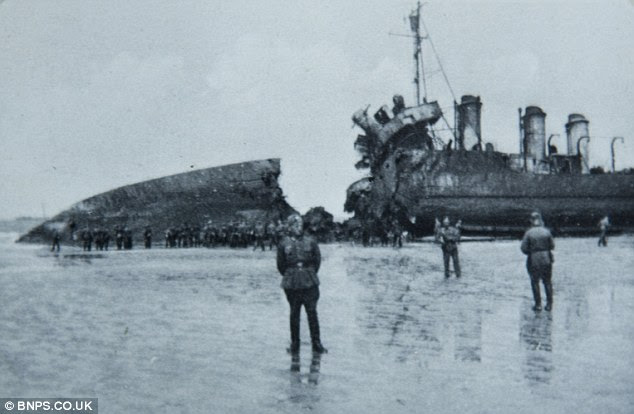 German troops examine a beached British ship with a giant hole in it 