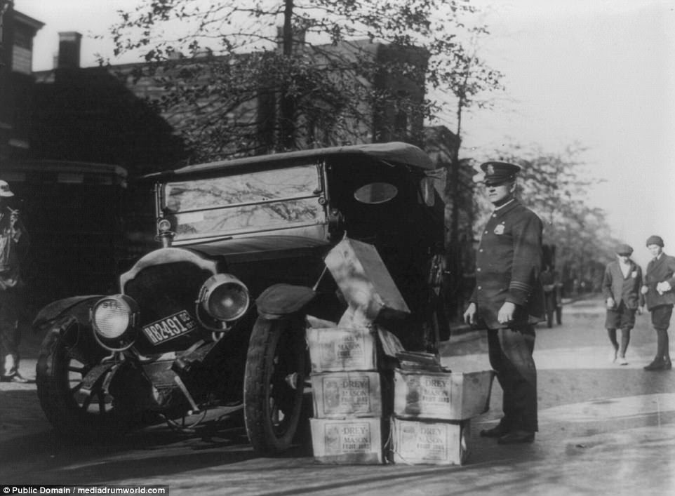 The agents were not paid very well for their services at the time, which made them easily influenced by bribes from gangsters and bootleggers. Here a Federal agent stands next to a wrecked car and several cases of moonshine 