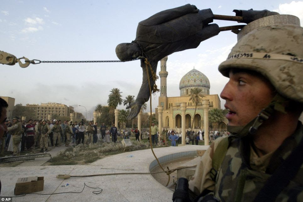 Then: Iraqi civilians and U.S. soldiers pull down a statue of Saddam Hussein in downtown Baghdad,on April 9 2003