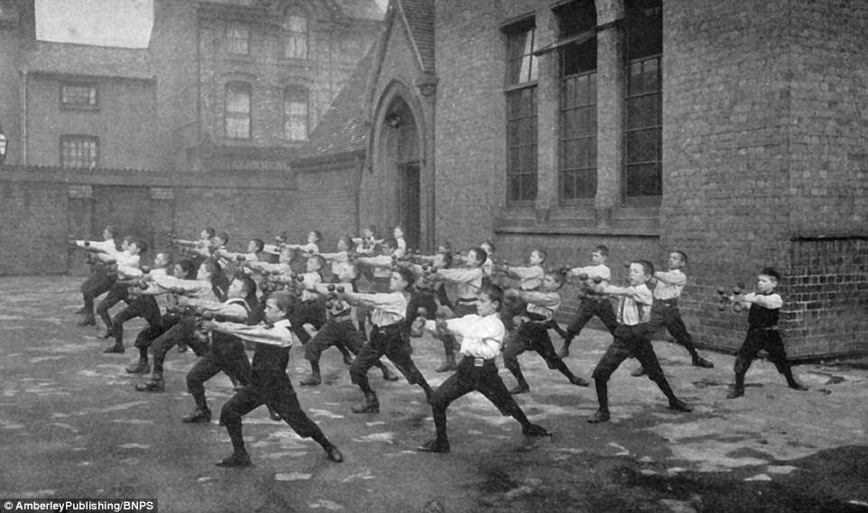 Boys are pictured in their PE lesson in the school playground  using barbells. Children were asked to help during the war as men were posted overseas to fight 
