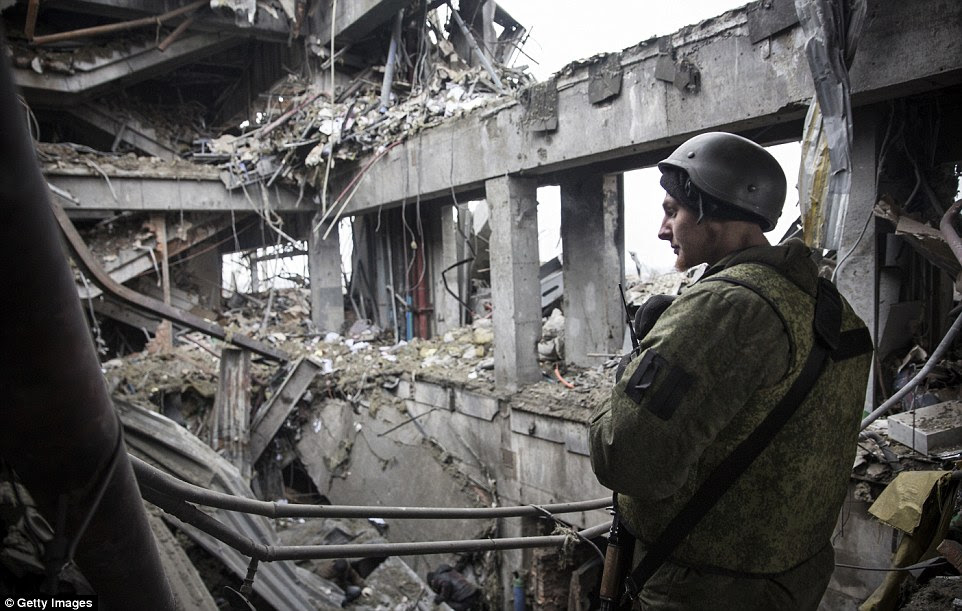 Rubble: A pro-Russian rebel stands guard while Ukrainian  prisoners of war are forced to search through the wreckage