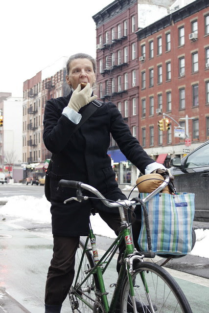 Woman eating muffin while resting on bicycle