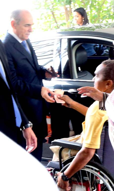 O ministro Marcelo Castro dá R$ 40 reais ao cadeirante Marcilio Pereira Silva Neto na porta do Ministério da Saúde - Ailton de Freitas / Agência O Globo