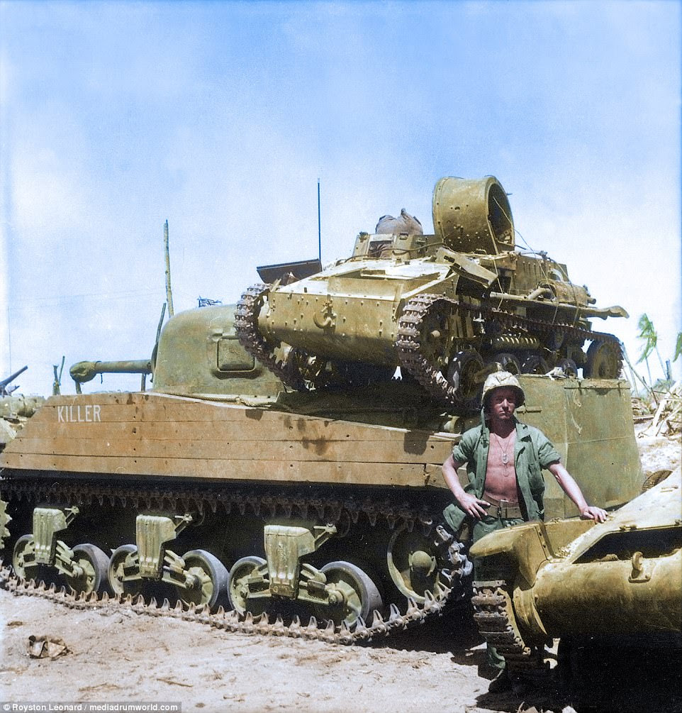 Pictured, Private First Class N. E. Carling stands beside the American M4 Sherman medium tank 'Killer' on Kwajalein Atoll