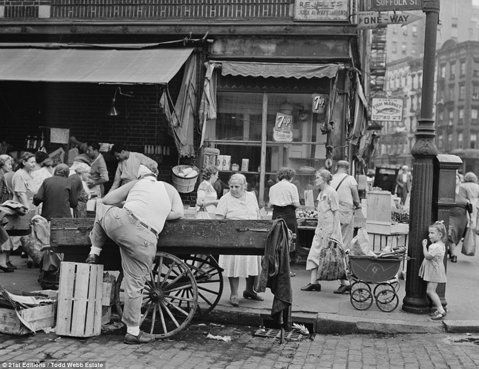 Commerce: This image shows traders on Suffolk Street, near Manhattan's Chinatown. There are street markets, pushcarts parked end to end in front of the endless rows of small stores