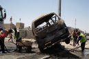 Street cleaners remove debris on the road at the site of a car bomb attack in Basra, southeast of Baghdad