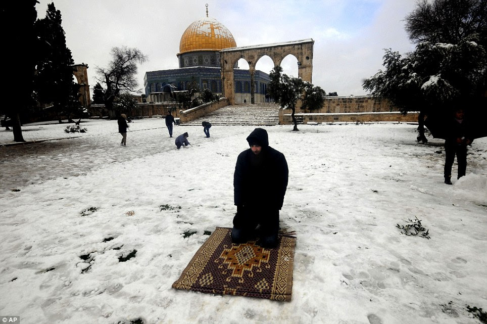 A Muslim man prays in the snow in front of the Dome of the Rock inside the Al-Aqsa Mosque compound of Jerusalem's old city